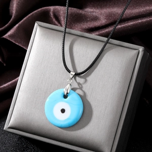 Detail of the blue glass Evil Eye pendant with clear textures and woven black rope chain