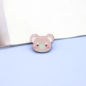 Detail of a cute cartoon koala enamel brooch with pink blush and mint green nose badge