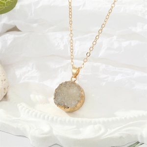 Detail van een witte natuurlijke kristallen hanger met gouden frame aan een O-ketting