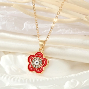 Detalle de collar con cadena dorada, flor de esmalte rojo y colgante de ojo turco