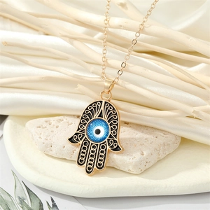 Collier Main de Fatma vintage avec pendentif œil bleu sur fond de pierre blanche élégante