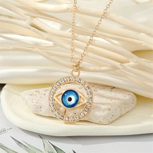 Collier vintage avec pendentif œil maléfique bleu et chaîne dorée sur pierres blanches