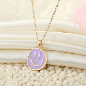 Macro shot of gold-plated smiley face necklace on lavender enamel pendant and satin