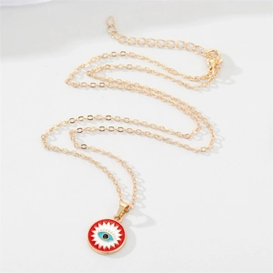 Detail of a golden chain with red Evil Eye pendant featuring white starburst and blue iris