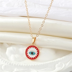 Detail of a gold evil eye pendant with vibrant colorful enamel on white silk background