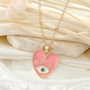 Gros plan du pendentif cœur en émail rose avec œil du diable sur une chaîne dorée