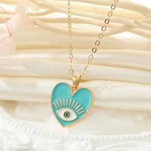 Détail macro du pendentif cœur œil protecteur émaillé vert sur fond en satin beige