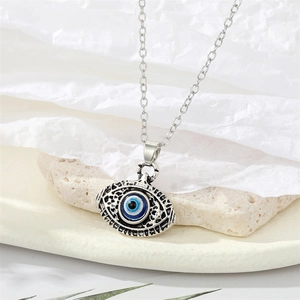 Macro-opname van een zilveren boze oog hanger met blauw email op een stenen basis
