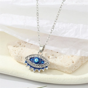 Vintage evil eye pendant necklace with blue stones and crystals on a stone base