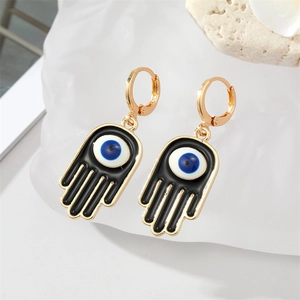 Boucles d'oreilles Main de Fatma gothiques en émail noir et œil bleu sur fond blanc neutre