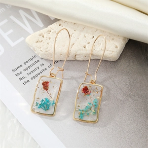 Detail view of rectangular resin earrings with embedded dried flowers and gold foil accents