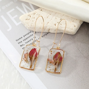 Detail of rectangular resin earring with dried rose buds and gold foil on stone