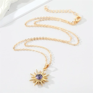 Gold sunburst necklace featuring a purple central gemstone on a delicate alloy chain