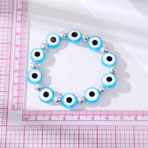 Detailed close-up of Evil Eye beaded bracelet with blue charms and silver beads on a scale