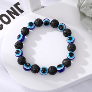 Bracelet fait main en perles de lave noire avec charmes œil bleu sur support blanc