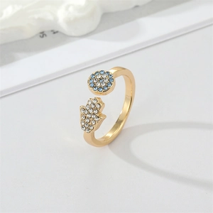 Gold Hamsa and Evil Eye open ring with colorful rhinestones on a white textured background