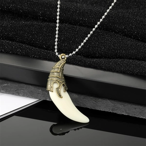 Détail du pendentif dent de loup vintage avec filigrane en bronze sur chaîne à billes