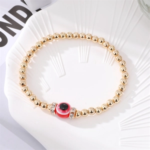 Handmade gold beaded bracelet featuring a red evil eye charm and sparkling accents