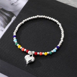 Colorful beaded bracelet with silver metal balls and a polished heart pendant on display