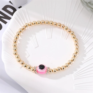 Detail of pink evil eye elastic bracelet with gold beads on a white decorative plate