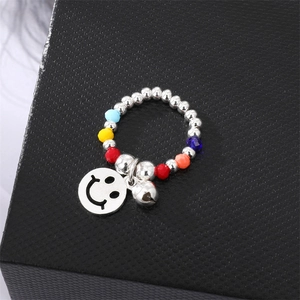 Close-up of a colorful beaded ring with silver balls and a smiley face bell charm