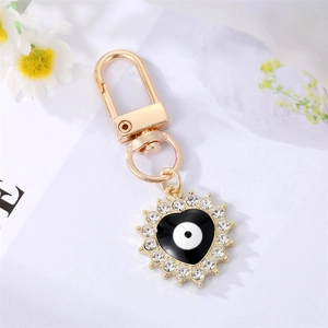 Detailed close-up of golden heart keychain with evil eye oil drip and sparkly rhinestones