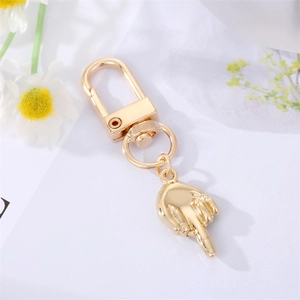 Detailed view of a gold-plated astronaut middle finger gesture keychain with D-ring clasp