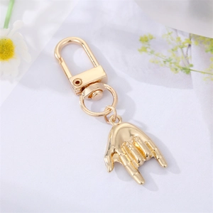 Detail of creative golden rock gesture keychain with lobster clasp and sleek metallic finish