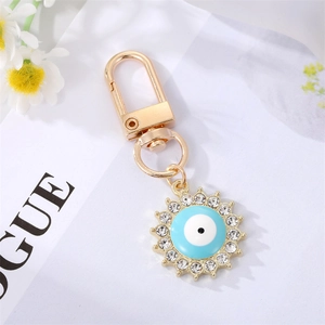 Close-up of golden sun keychain with sparkling crystals and blue evil eye detail