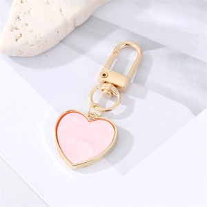 Detailed macro shot of a heart-shaped keychain with marble pink texture and gold alloy frame