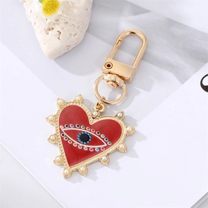 Portachiavi a cuore Evil Eye dorato con smalto rosso e perle su sfondo bianco