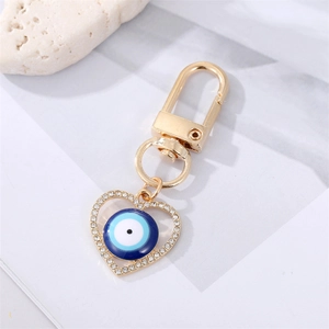 Detail of gold heart-shaped evil eye keychain with white rhinestones and D-ring clasp