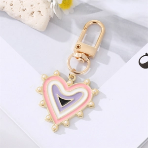 Portachiavi a cuore dorato con smalto rosa, perle e ciondolo occhio blu su sfondo bianco