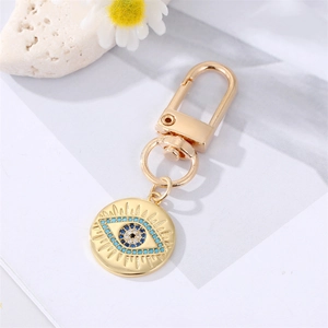 Macro shot of evil eye keychain with blue crystals and gold finish on white background