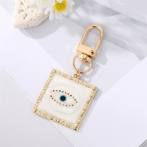 Macro shot of evil eye heart keychain with colorful crystal accents on white floral background