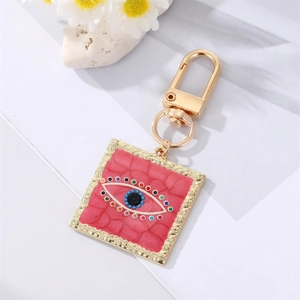 Detail of evil eye keychain with pink crocodile texture and golden lobster clasp