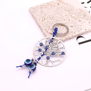 Détail du porte-clés arbre de vie avec perles œil bleu et corde tressée sur fond de pierre