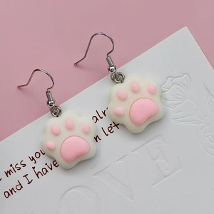 Close-up of cute cat paw drop earrings with pink pads on a decorative white card