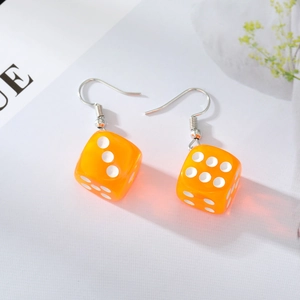 Close-up of trendy orange resin dice earrings with silver hooks on a stylish background