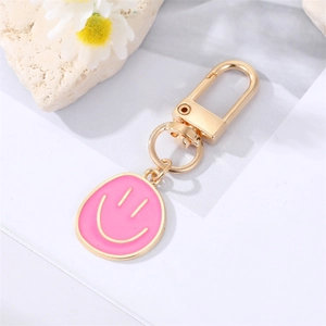 Chic gold-plated smiley face keychain with pink enamel pendant on a white background