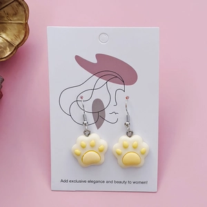 Cute resin cat paw dangle earrings in cream and yellow on white card display