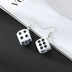 Minimalist white dice earrings with silver metal hooks on a stylish black and white background