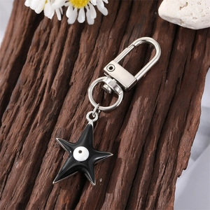 Llavero de estrella con esmalte negro y ojo turco sobre fondo de madera rústica