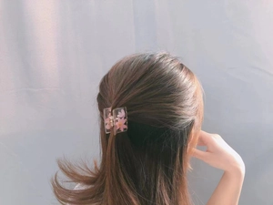 Détail d'une pince à cheveux en résine transparente avec fleurs roses sur cheveux mi-clos