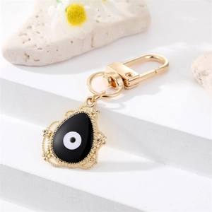 Detalle del llavero ojo turco dorado con esmalte negro y borde de encaje de metal fino
