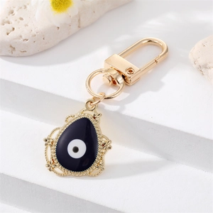 Detalle de un llavero de ojo turco dorado con esmalte azul sobre una base de piedra blanca