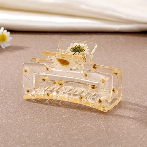 Détail d'une pince à cheveux en résine transparente avec des marguerites séchées