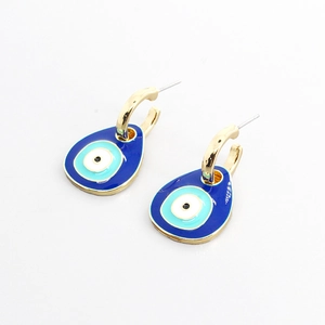 Fashionable gold evil eye drop earrings with blue enamel charms on a white background