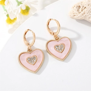 Close-up of pink heart dangle earrings with crystal inlay and gold-tone huggie hoops