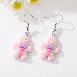 Détail de boucles d'oreilles bonhomme pain d'épice en résine rose avec nœud violet mat